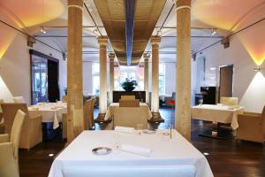 un restaurante con mesas blancas, sillas y columnas en Hotel Ketschauer Hof, en Deidesheim