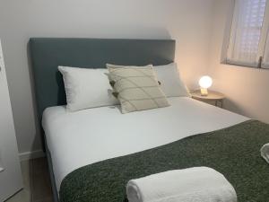 ein Bett mit weißen Kissen und einer grünen Decke in der Unterkunft Torreira Vacation Homes - Ria House in Torreira