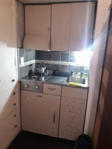 una pequeña cocina con armarios blancos y fregadero en CARLOS PAZ, Dpto, 3 Huésped en Villa Carlos Paz