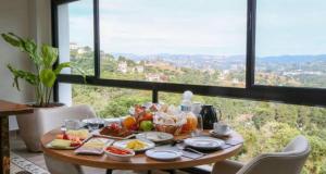 a table with food on it in front of a window at Carpe Diem Hotel Duplex in Campos do Jordão