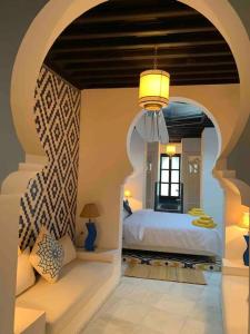 Un dormitorio con un arco y una cama. en Asilah * Dar Badiaa * Riad vue sur l’Atlantique, en Asilah