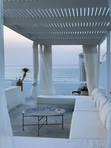 una sala de estar con muebles blancos y vistas al océano. en Asilah * Dar Badiaa * Riad vue sur l’Atlantique, en Asilah