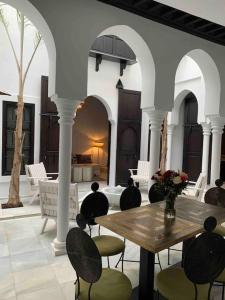 Asilah * Dar Badiaa * Riad vue sur l’Atlantique في أصيلة: فناء مع طاولة وكراسي خشبية وغرفة