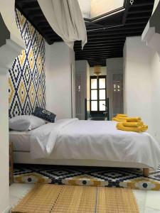 sypialnia z dużym łóżkiem z żółtymi ręcznikami w obiekcie Asilah * Dar Badiaa * Riad vue sur l’Atlantique w mieście Asila