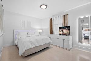 a white bedroom with a bed and a tv at Beautiful Apartment in the Heart of Miami Apt 3 in Miami