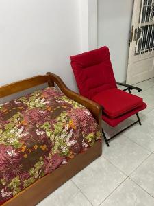 1 dormitorio con 1 cama y 1 silla roja en Edificio Aquarone 001, en Piriápolis