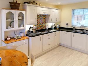 a kitchen with white cabinets and a sink and a table at Platform 10 in Bideford