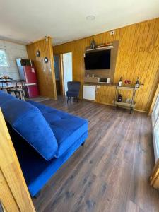 sala de estar con sofá azul y TV en Cabañas Borde Lindo, en Valdivia