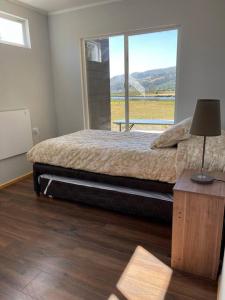 1 dormitorio con cama y ventana grande en Cabañas Borde Lindo, en Valdivia