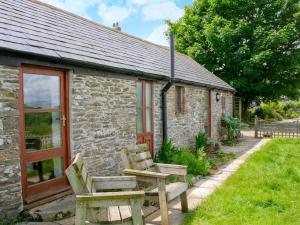 a stone cottage with two wooden chairs in front of it at The Mealhouse-UK12902 in Pelynt