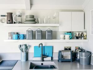 a kitchen with white cabinets and a sink with blue appliances at Phoebes Folly-uk36581 in Milton Abbot