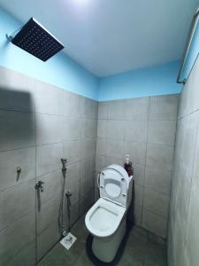 a bathroom with a toilet with a light on the ceiling at Cabin stay with Sunrise and plane spotting view in Shah Alam