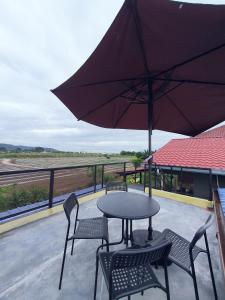 a patio with a table and chairs and an umbrella at Cabin stay with Sunrise and plane spotting view in Shah Alam