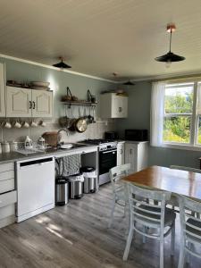 a kitchen with white cabinets and a table and chairs at Wisteria Way in Opononi