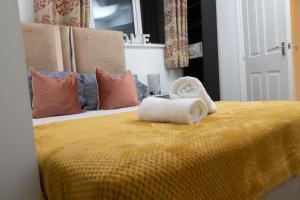 Un dormitorio con una cama amarilla con una toalla. en Broughton Haven 5 Beds House Free WiFi, Free parking, NETFLIX, en Milton Keynes
