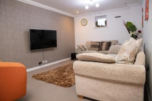 sala de estar con sofá y TV de pantalla plana en Broughton Haven 5 Beds House Free WiFi, Free parking, NETFLIX, en Milton Keynes