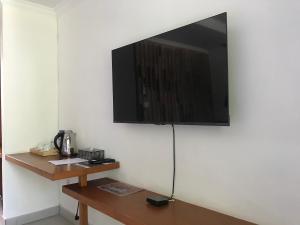 telewizor z płaskim ekranem wiszący na białej ścianie w obiekcie Soda Resort Gili Trawangan w Gili Trawangan