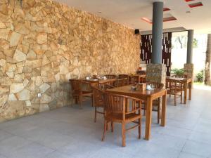 a restaurant with wooden tables and chairs and a stone wall at Soda Resort Gili Trawangan in Gili Trawangan