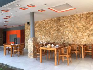 a restaurant with wooden tables and chairs and a stone wall at Soda Resort Gili Trawangan in Gili Trawangan