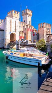 a boat in the water in front of a castle at PAGANINI suits and apartments in Sirmione