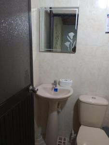 a bathroom with a toilet and a sink and a mirror at Hotel Bethesda in Aguachica