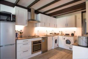cocina con armarios blancos, lavadora y secadora en A Bright and Spacious Gem-Newly renovated house, en Staines