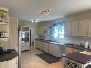 a large kitchen with wooden cabinets and a refrigerator at ‘JASPER’ Private Room with shared bathroom in Saint Philip