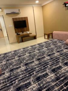 a living room with a couch and a tv at نزل سمايا للشقق الفندقية in Al Hofuf