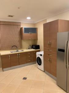 a kitchen with a refrigerator and a washing machine at نزل سمايا للشقق الفندقية in Al Hofuf