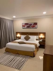 a bedroom with a large bed with two lights on it at نزل سمايا للشقق الفندقية in Al Hofuf +28 photos