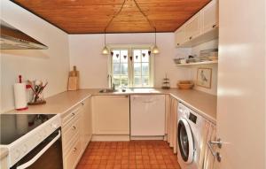 a kitchen with white cabinets and a washer and dryer at Holiday Home Fanø 55 in Sønderho