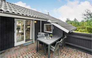 une maison noire avec une table et des chaises sur une terrasse dans l'établissement Nice Home In Hemmet With Kitchen, à Hemmet