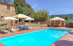 a swimming pool with chairs and umbrellas next to a building at Beautiful Home In Castiglion Fiorentino With Kitchen in Pergognano