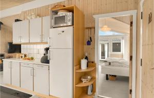 cocina con armarios blancos y nevera blanca en Awesome Home In Lkken With Wifi, en Løkken