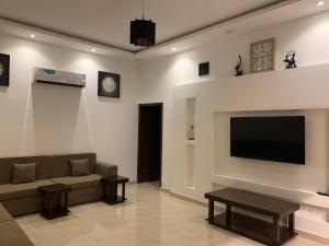 uma sala de estar com um sofá e uma televisão de ecrã plano em فيلا المنزل em Meca