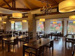 a dining room with tables and chairs and windows at Greenpia Yame in Yame