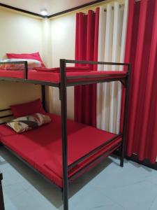 Ce dortoir comprend 2 lits superposés et des rideaux rouges. dans l'établissement 30pax-Jumongs Transient Inn, à Bantay