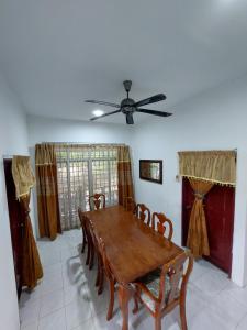 una sala da pranzo con tavolo, sedie e ventilatore a soffitto di HOMESTAY BONDA PASIR MAS, KELANTAN a Pasir Mas