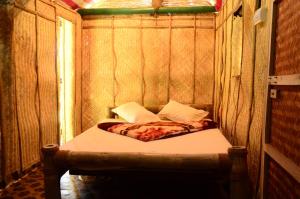 a small bed in a wooden walled room at Greenways Tree House and Mud House in Chekadi