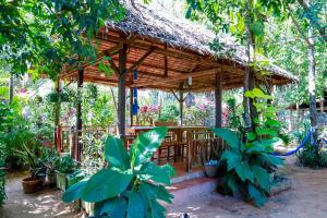 a wooden gazebo in a garden with plants at Community Homestay - BAKONG 
