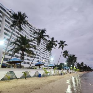 a large building on the beach with palm trees at Beachfront, Juandolio in Juan Dolio