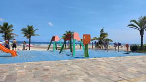 a playground on a beach with palm trees and the ocean at Pousada Vila Real PG in Praia Grande