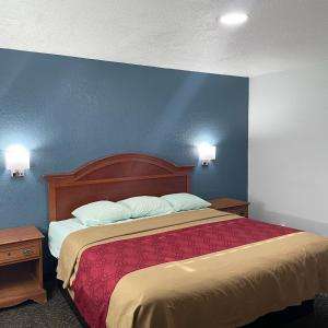 een slaapkamer met een bed met een blauwe muur bij Budget Inn Madill in Madill