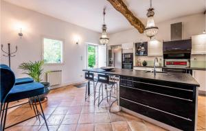 a kitchen with a large black counter and blue stools at Awesome Home In Marquefave With Wifi, Swimming Pool And 3 Bedrooms in Marquefave