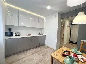 cocina con armarios blancos y mesa de madera en Уютная квартира в центре, en Pavlodar