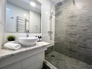 uma casa de banho com um lavatório e uma cabina de duche em vidro. em Уютная квартира в центре em Pavlodar