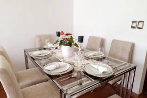 une table en verre avec des assiettes et un vase avec une fleur dans l'établissement Apartment 4 Rent - Av San Borja Norte Cdra 8, à Lima