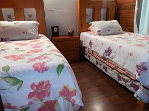 - une chambre avec 2 lits et des draps fleuris dans l'établissement Cabaña de las Flores. Magia en la laguna, à Santa María del Oro