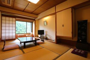 a living room with a table and a tv at Momijiya Honkan Takaosansou in Kyoto