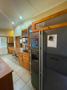 eine Küche mit einem Kühlschrank aus Edelstahl und Holzschränken in der Unterkunft Repose Guest house! in King Williamʼs Town